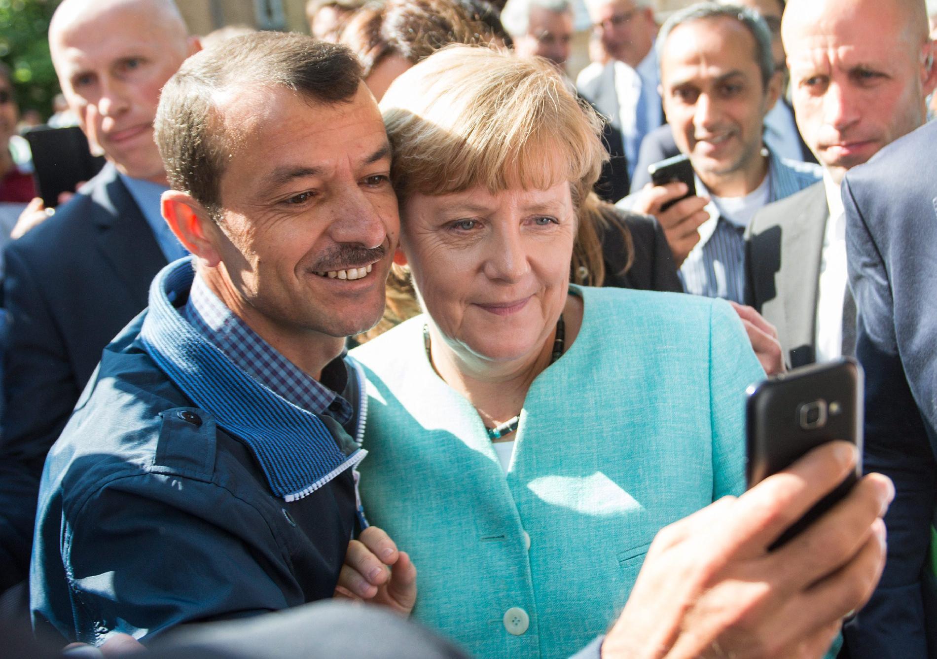 Angela Merkel német kancellárral készít közös felvételt egy menekült a német szövetségi bevándorlás- és menekültügyi hatóság egyik berlini befogadóállomásán 2015. szeptember 10-én