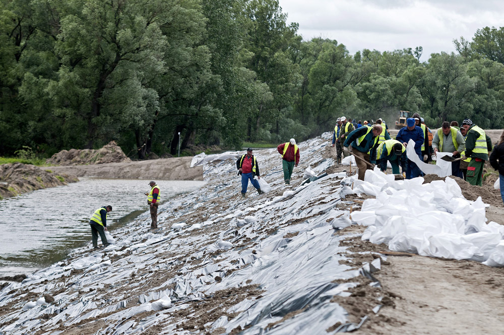 Munkások dolgoznak a várható árhullám miatt a Mosoni-Duna gátjának megerősítésén és magasításán Győrújfalu határában