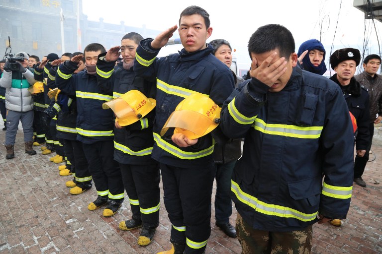 Kínai tűzoltók tisztelegnek a tragédiában elhunyt társaik előtt.