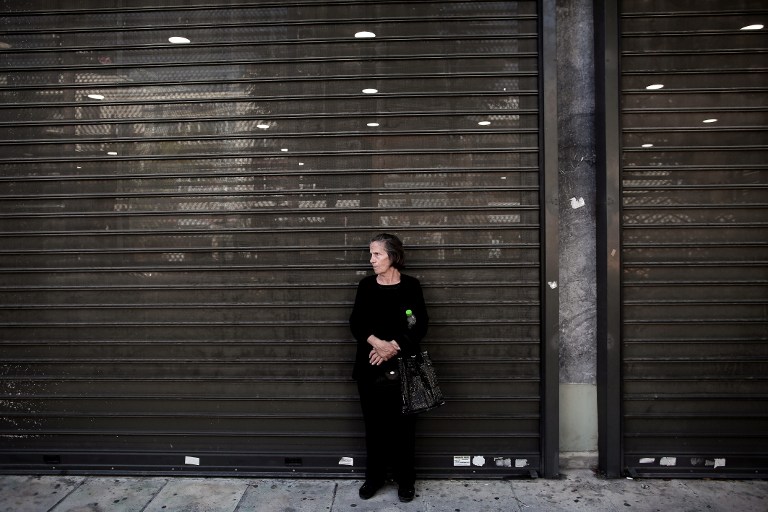 Nyugdíjas hölgy várakozik a Görögország Nemzeti Bankja előtt, hogy hozzájusson pénzéhez
